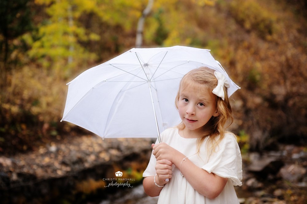 young gir wearing white dress with white umbrella