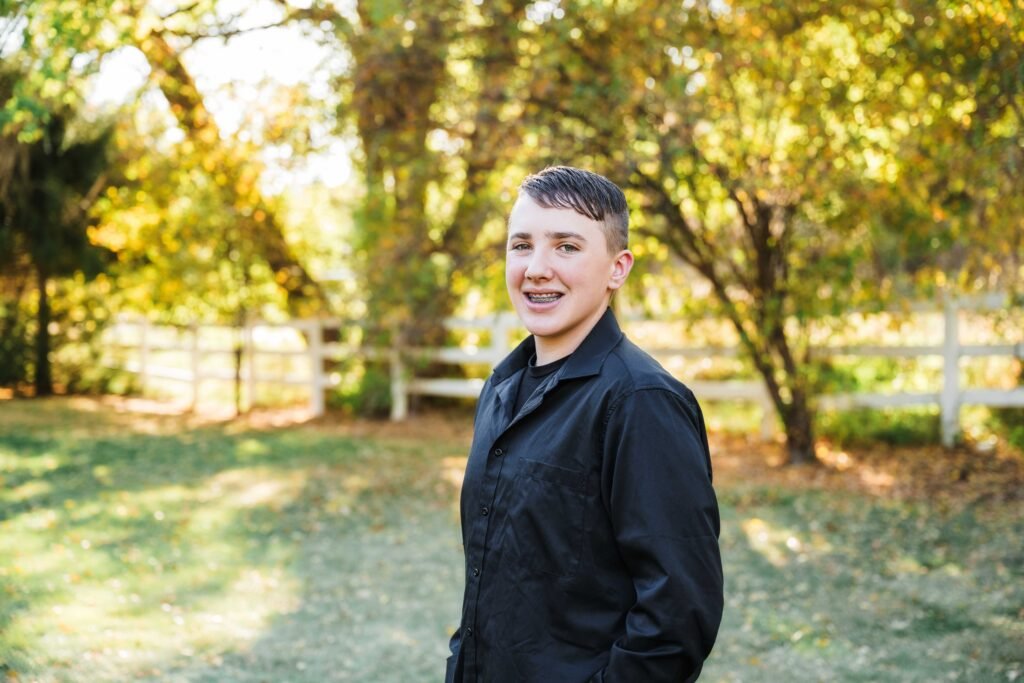 teenage boy, wearing jean and a black button down shirt, at a park