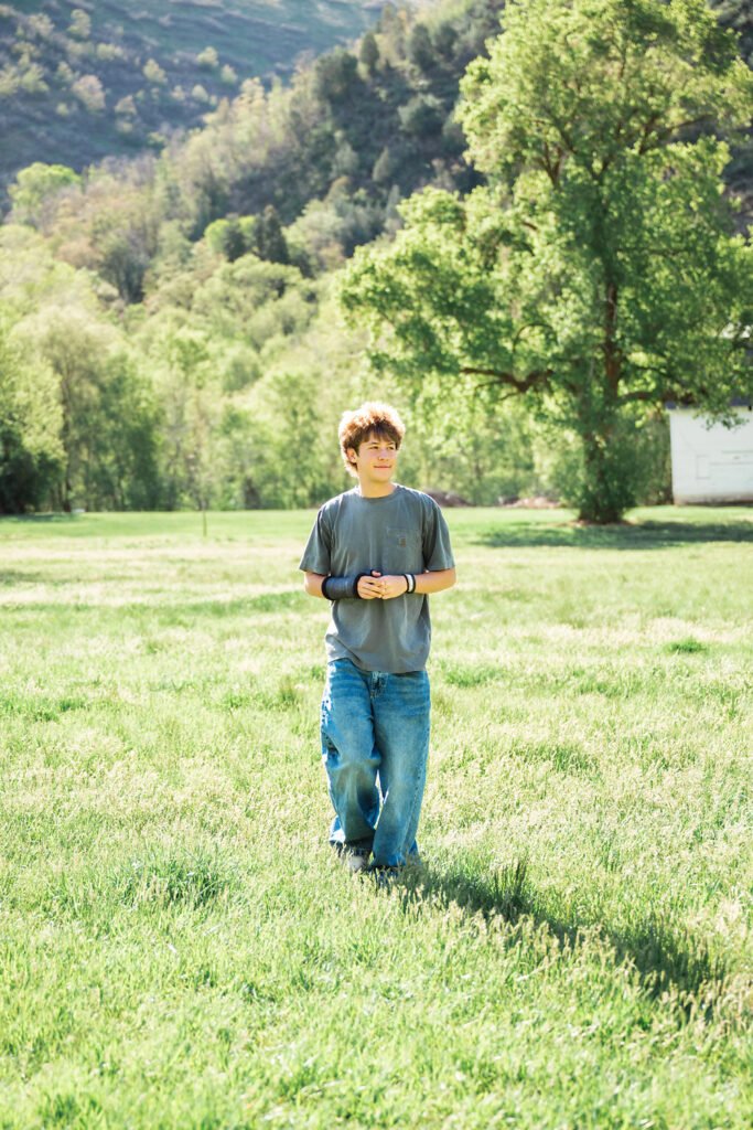 Utah High School Senior Boy walking in a grassy field