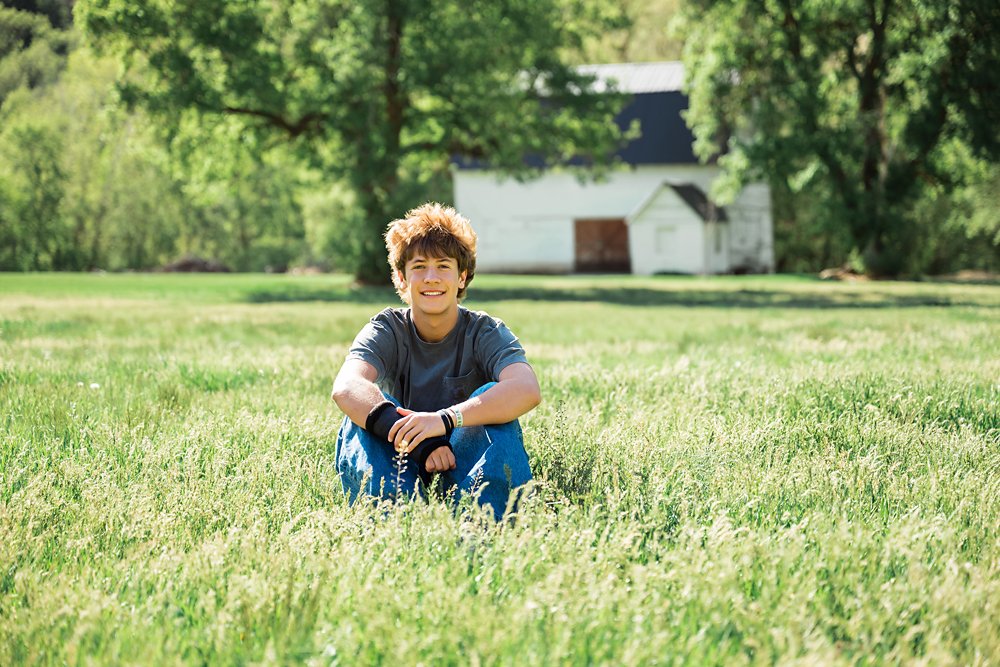 Utah High School Senior Boy sitting in a grassy field