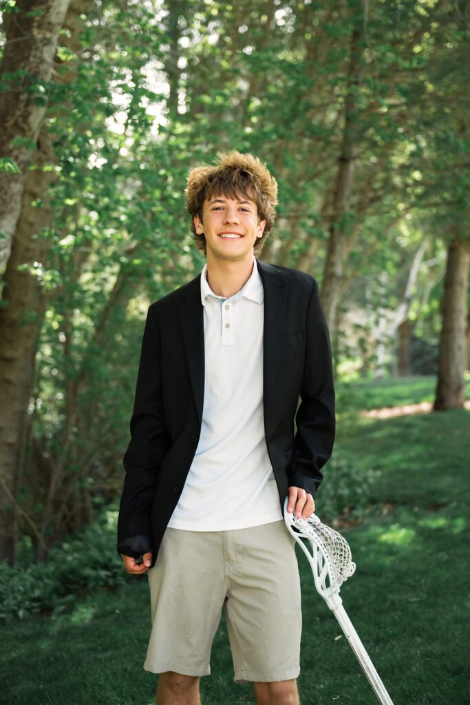 Utah High School Senior Boy with lacrosse stick wearing a polo shirt and jacket